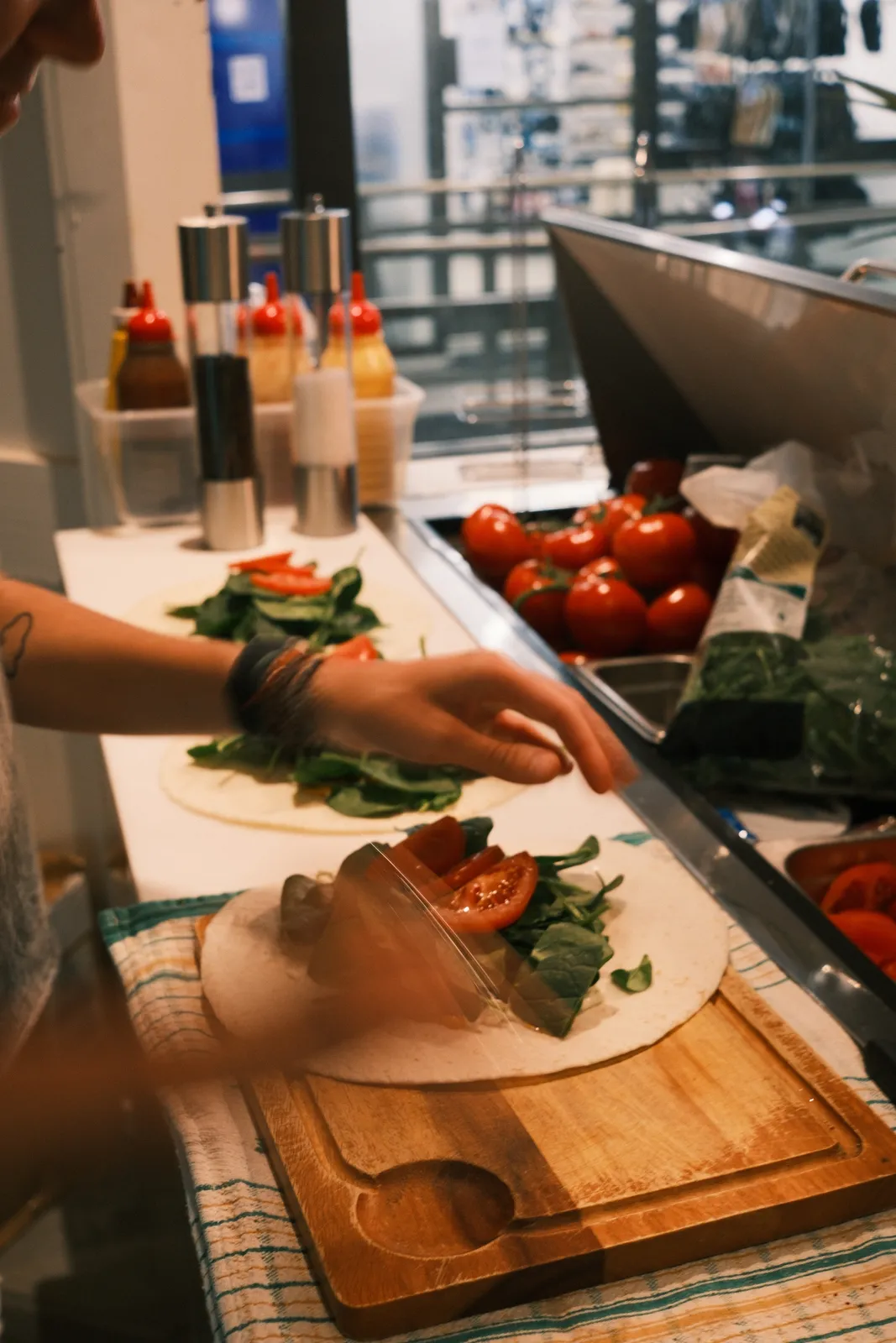 A wrap being filled with spinach and tomato.