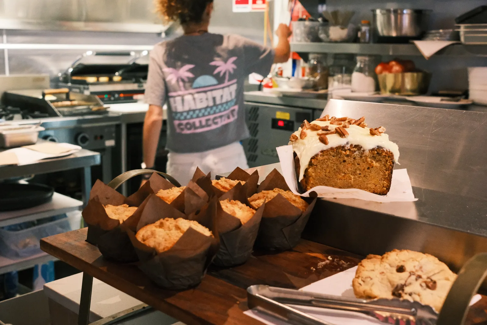 Muffins, cakes and a cookie on the counter, with the kitchen behind.